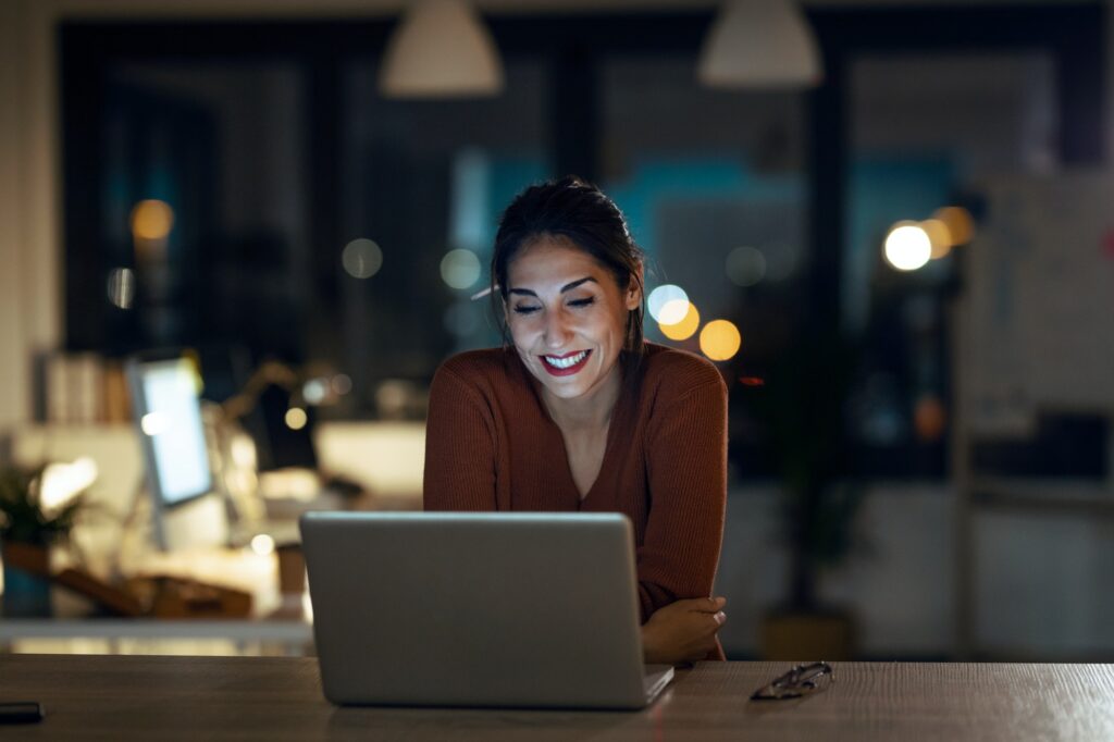 smiling beautiful business woman at home looking at her newly designed website on her laptop.