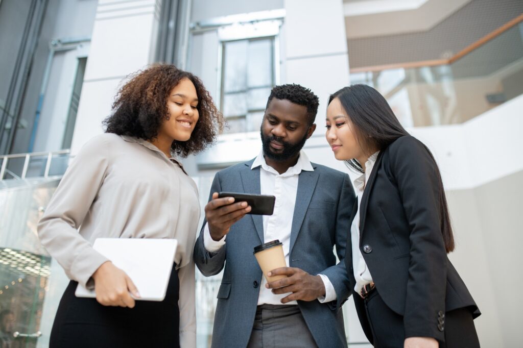 three business professionals looking in a mobile phone searching for packages for digital marketing services at gabbarinfo.com